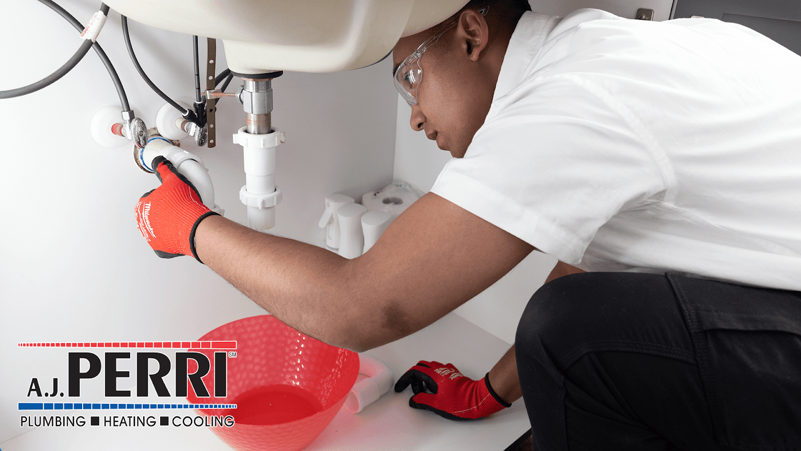 Plumber in Long Branch, NJ, fixing under-sink pipes in home.